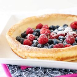Fresh mixed berry galette with dusted powdered sugar on a white plate.