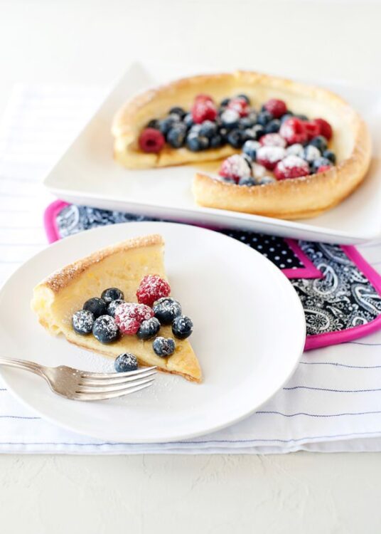 Fresh fruit tart with mixed berries and powdered sugar on a white plate, best baked dessert recipe from Baked Bree.