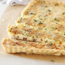 Flaky vegetable quiche with crispy crust and fresh herbs.
