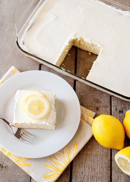 Lemon dessert with creamy white frosting and fresh lemon slices on a white plate.