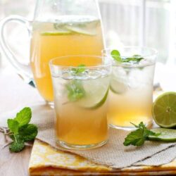 Refreshing citrus mint pitcher and glasses of lime mint iced tea on a wooden table.