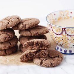 Chocolate crinkle cookies with a glass of milk on marble surface.