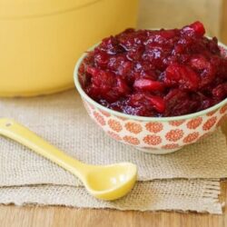 Fresh homemade strawberry compote in a decorative bowl on a wooden table.
