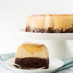 Chocolate and caramel cheesecake with a graham cracker crust on a white plate.
