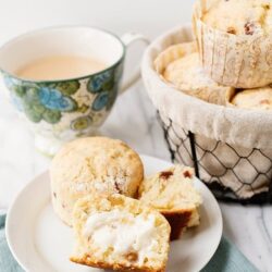 Fluffy homemade scones with melted butter and jam, served with a cup of tea. Perfect for breakfast or afternoon tea.