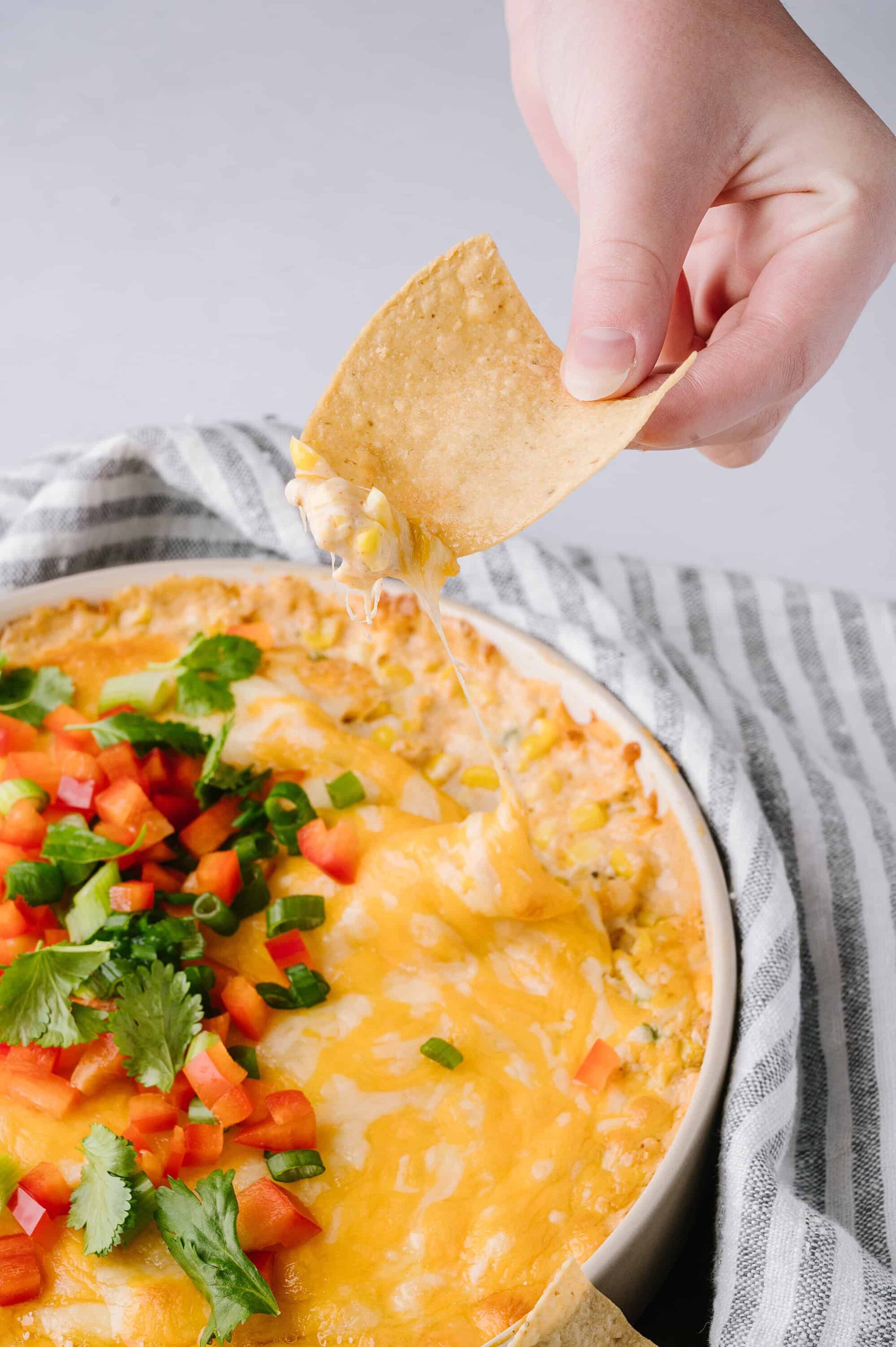 Creamy cheese dip with fresh vegetables and tortilla chips, perfect for snacks or party appetizers.