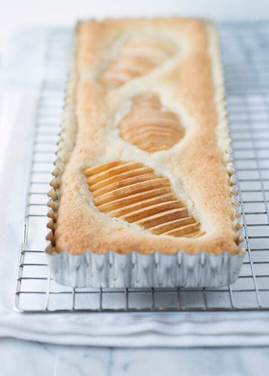 Slices of baked pear cinnamon bread in a loaf pan on a cooling rack.