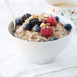 Creamy oatmeal topped with fresh berries and sliced almonds, served in a white bowl.