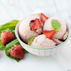 Creamy strawberry ice cream with fresh strawberries and basil garnish. Perfect homemade dessert from Baked Bree.