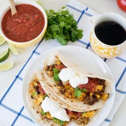Fresh beef and veggie tacos with sour cream, cilantro, and salsa in a cozy setting.