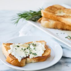 Buttered toast with mashed potatoes and herbs on a white plate.