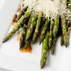 Roasted asparagus with Parmesan cheese on white plate.