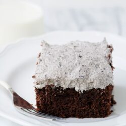 Rich chocolate cake with cookies and cream frosting on a white plate.