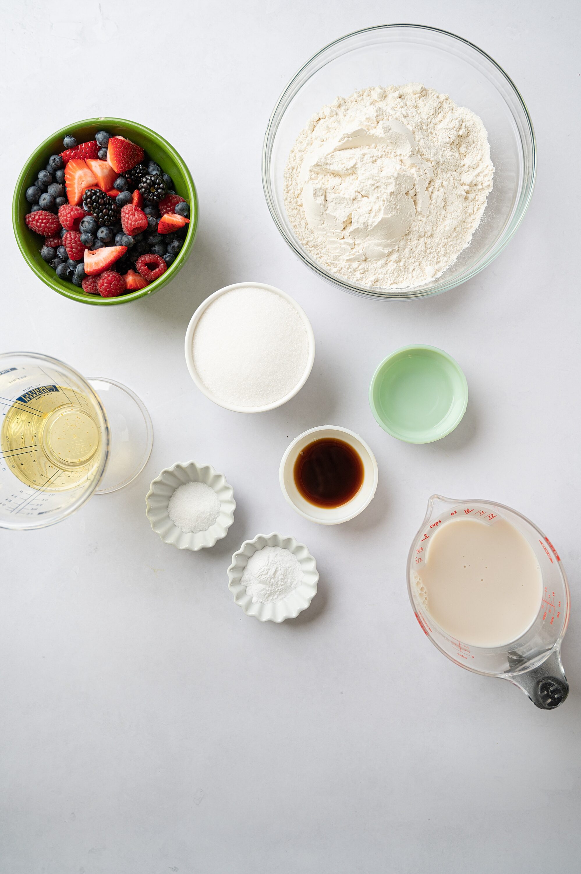 Fresh berries and baking ingredients for fruit tart on white background.