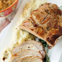 Baked Bree, roast pork tenderloin with mashed potatoes and gravy, served with herbs and vegetables.
