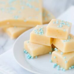 Buttery white chocolate fudge squares with pastel blue sprinkles on white plate.