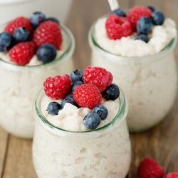 Creamy ricotta dessert topped with fresh raspberries and blueberries, served in glass jars.