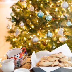 Festive holiday cookies and hot cocoa near decorated Christmas tree.