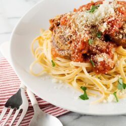 Creamy spaghetti with meatballs and tomato sauce topped with grated Parmesan cheese.