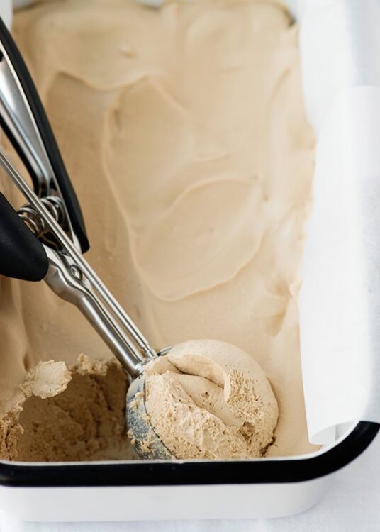Creamy cookie dough being scooped from a ice cream maker.