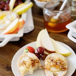 Cream cheese Danish pastry with sliced almonds and fresh fruit on a white plate.