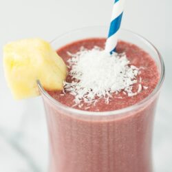 Creamy strawberry pineapple smoothie with shredded coconut and pineapple garnish.