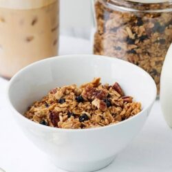 Crunchy homemade granola with oats, nuts, and dried fruits in a white bowl.