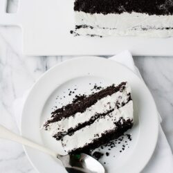 Layered Oreo cookie ice cream cake with chocolate cookie crumbs and cream filling.