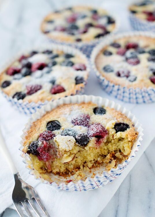 Fresh blueberry lemon muffin with powdered sugar topping in cupcake liner.