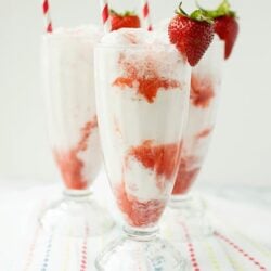 Fresh strawberry banana milkshake with whipped cream and strawberries on top, served in vintage glassware.