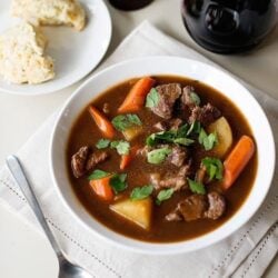 Hearty beef stew with vegetables and herbs served with bread and a glass of red wine. Perfect comfort food for cold days.