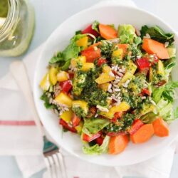 Bright vegetable salad with bell peppers, carrots, and sunflower seeds in a white bowl.