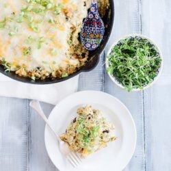 Cheesy baked casserole with green onions served with fresh microgreens and a side dish, baked in a cast-iron skillet.
