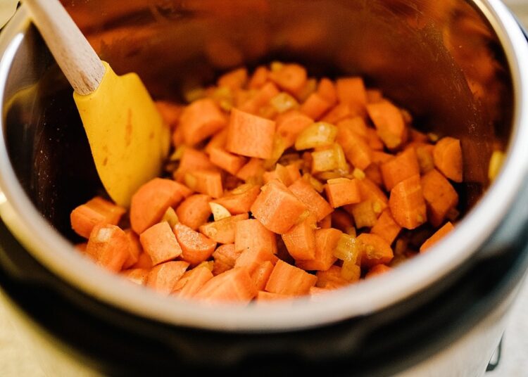 Diced sweet potatoes cooking in an Instant Pot with a silicone spatula, ready for a nutritious recipe.