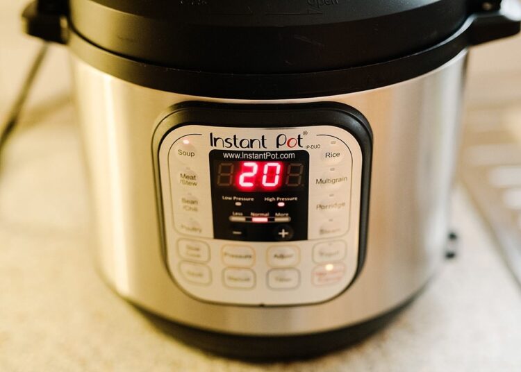 Cream-colored Instant Pot digital multi-cooker with a control panel displaying a cooking time of 20 minutes, ready for meal preparation, on a kitchen countertop.