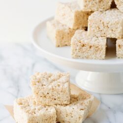 Fluffy rice cereal treats with marshmallows on marble surface.