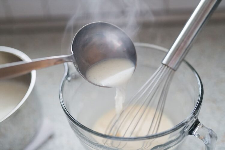 Cream being poured into a mixing bowl with a whisk, perfect for baking recipes.