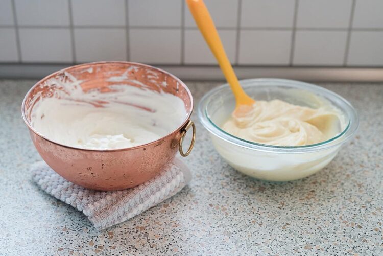 Light whipped cream in copper and glass bowls on kitchen countertop.
