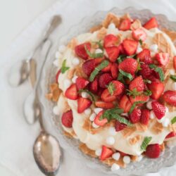 Fresh strawberry shortcake dessert with whipped cream and crispy pastry layers on a glass cake stand.