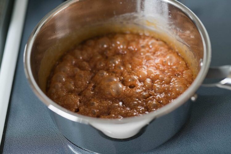 Creamy caramel sauce simmering in a stainless steel pot for baking or dessert recipes.