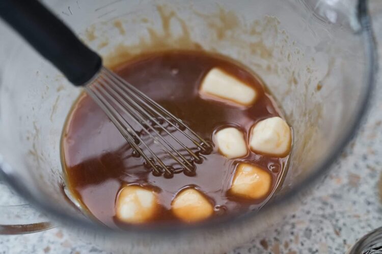 Creamy melting butter in chocolate mixture with a whisk for baking or dessert recipes.
