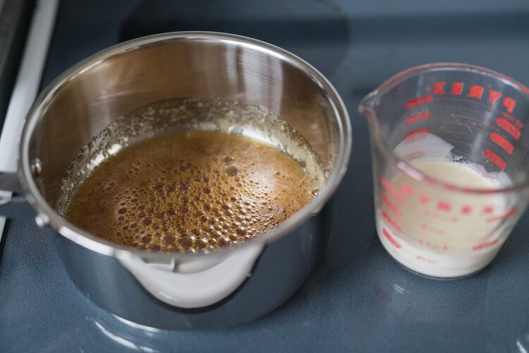 Frothing milk in stainless steel pitcher on stove for baking or coffee recipes.