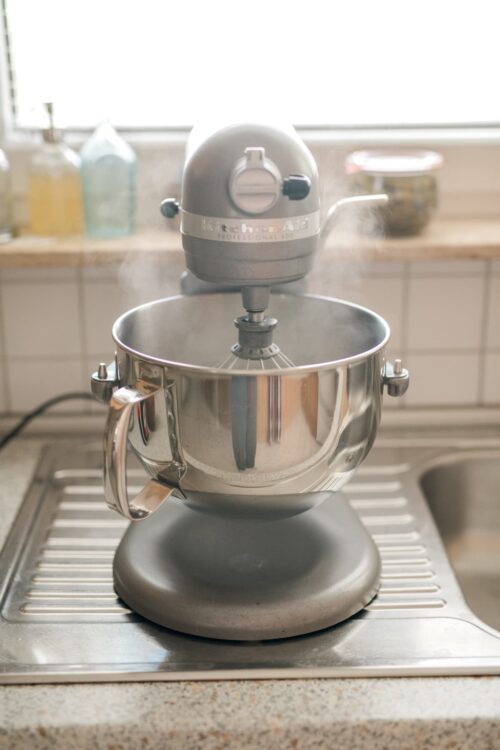 Shiny stand mixer on kitchen countertop with steam rising, ideal for baking recipes.