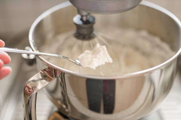 Cream being added to a stand mixer with a metal bowl for baking recipes.