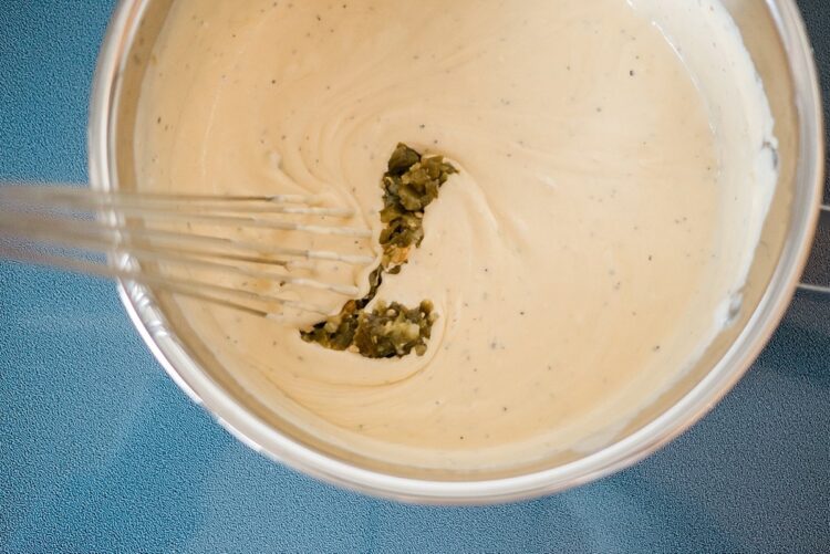 Creamy pickle relish mixture in a mixing bowl with a whisk, ready for baking or cooking.