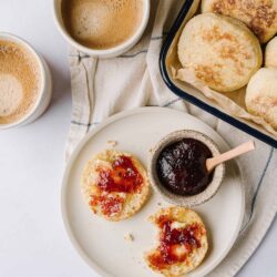 Fluffy biscuits with strawberry jam and coffee on a breakfast table.