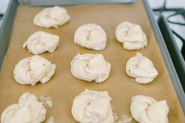 Cream cheese cinnamon roll dough on baking sheet with parchment paper, ready for baking.