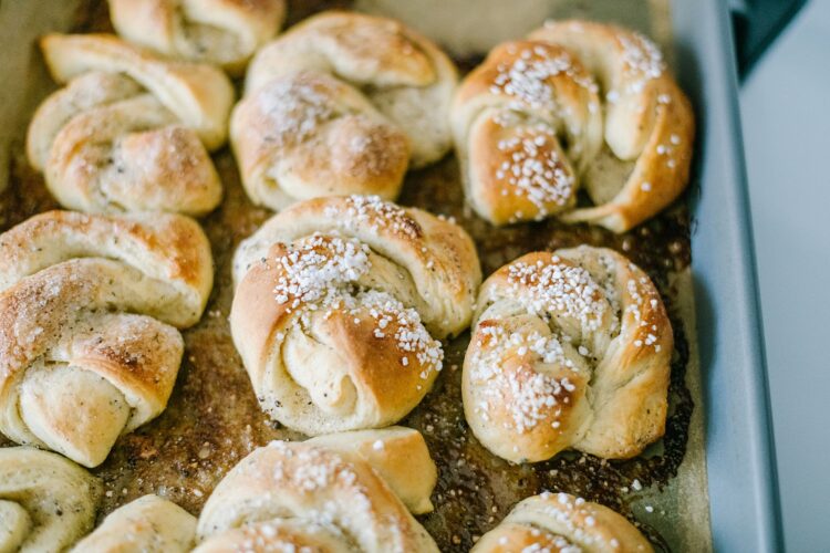 Buttery homemade cinnamon rolls with pearl sugar topping on a baking sheet.