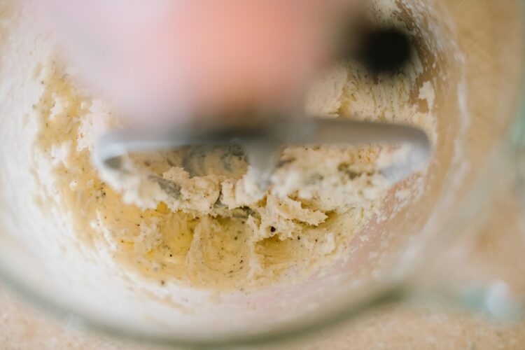 Creamy cookie dough in a mixing bowl with a hand mixer.