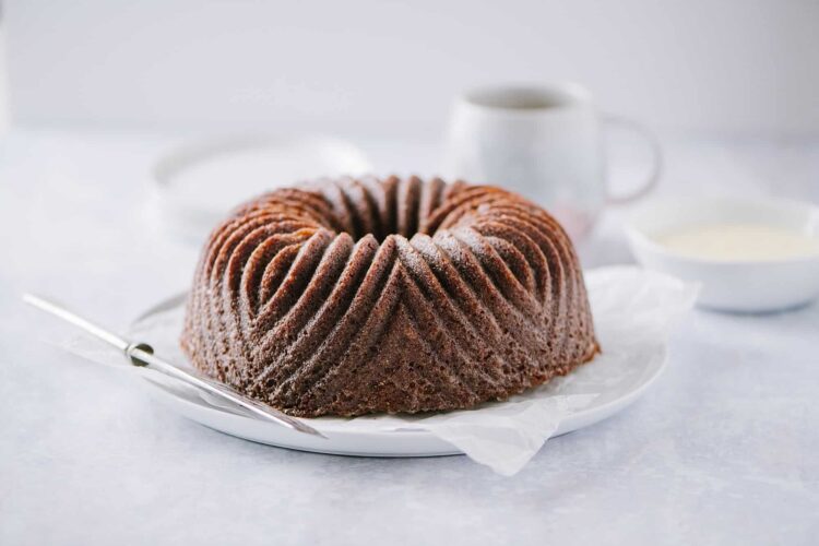 Orange Gingerbread Bundt Cake with powdered sugar on a white plate, perfect for baking and dessert recipes.